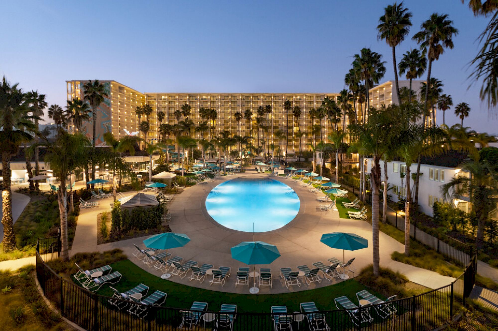 View of a hotel pool with palm trees at dusk