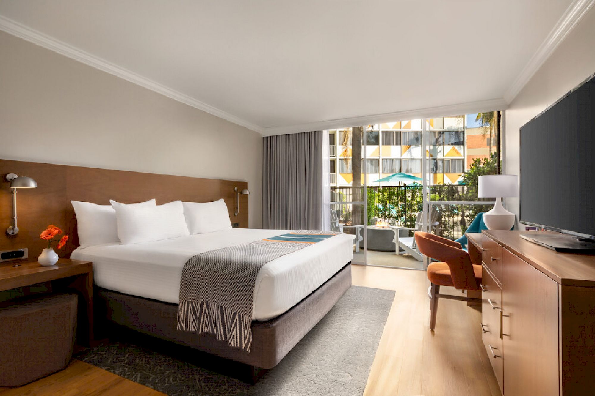 modern hotel guest room with a king bed, modern furnishings, and sliding doors opening to a private patio with a fire pit
